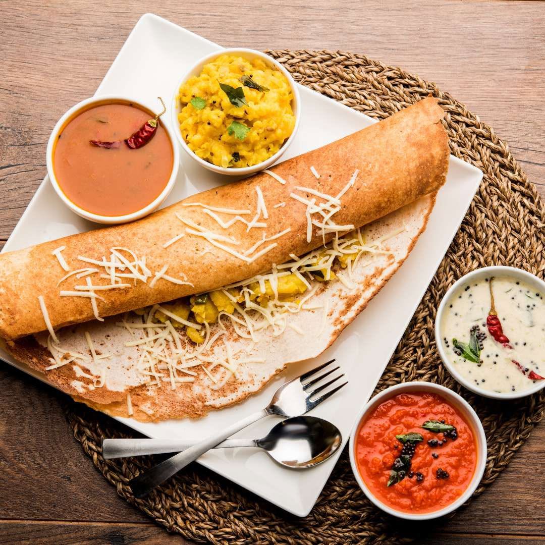 A dosa served with sambar, chutney and potato filling